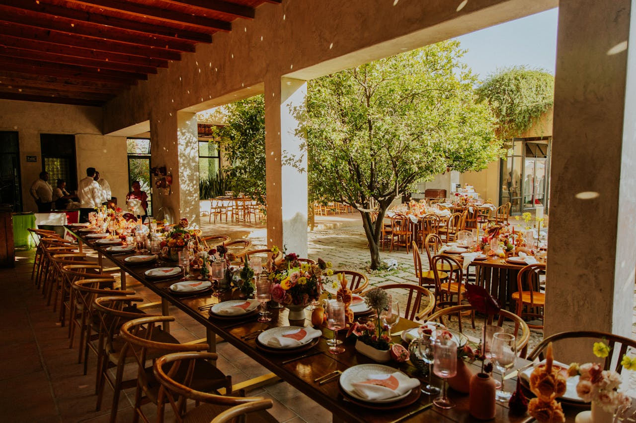 Services Charming outdoor wedding reception featuring long tables with floral centerpieces under open sky.